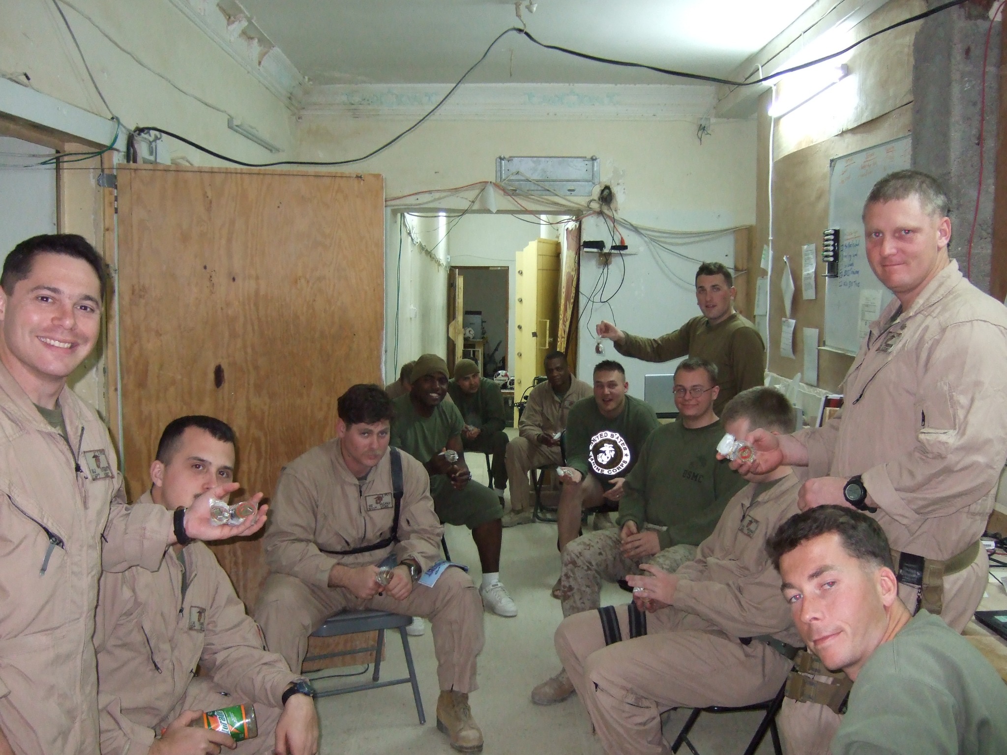Group of service members in a deployed setting holding challenge coins